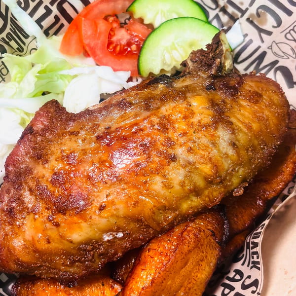 Crispy fried chicken with plantains, lettuce, tomato, and cucumber in a basket from The Jungle Plate.