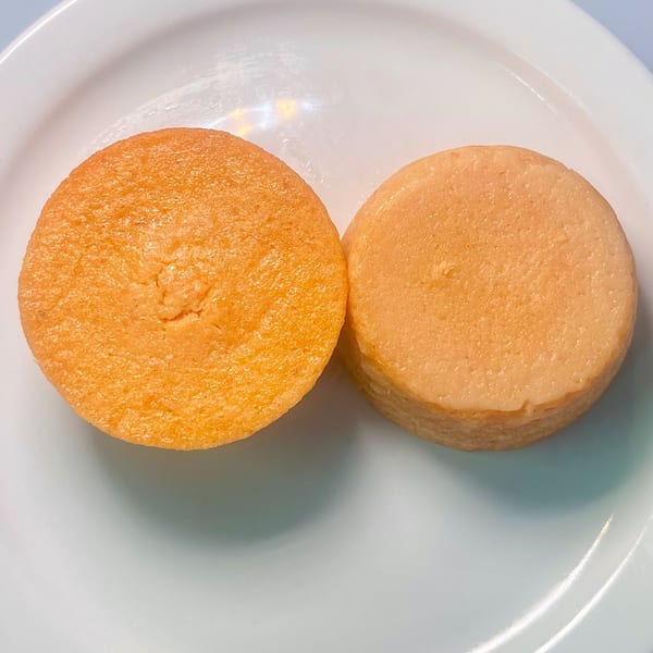 Two round, golden-brown African-fusion cakes, one slightly taller, on a white plate.