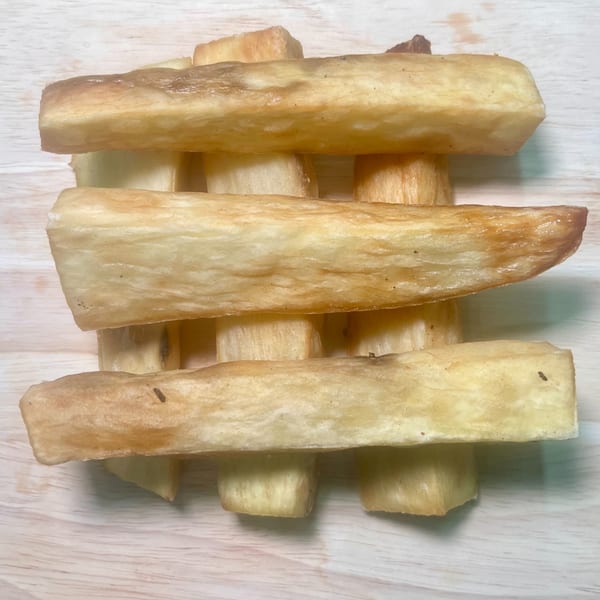 Golden brown fried cassava sticks, a popular African-fusion side dish, arranged on a light wooden surface.