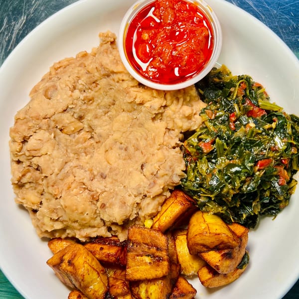 A Jungle Plate meal with mashed beans, stewed greens, fried plantains, and a side of red sauce.