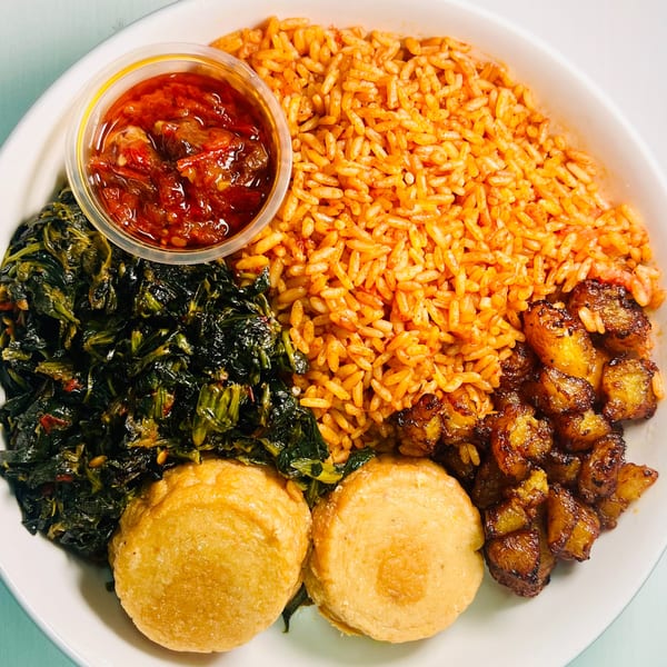 A Jungle Plate meal with jollof rice, stewed greens, fried plantains, two corn fritters, and red sauce.